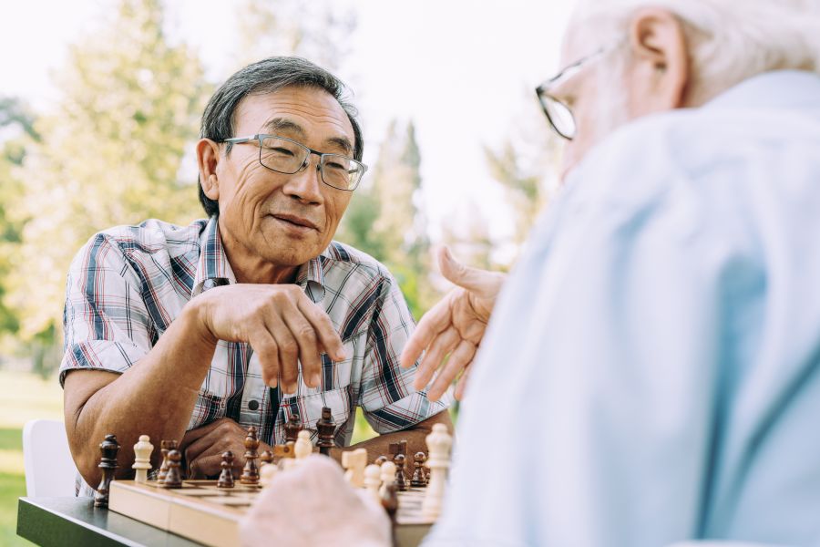 Two seniors playing chess outdoors.