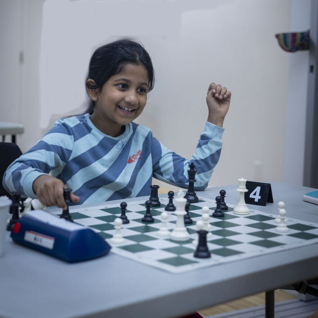 Girl playing chess punches in on the chess clock.