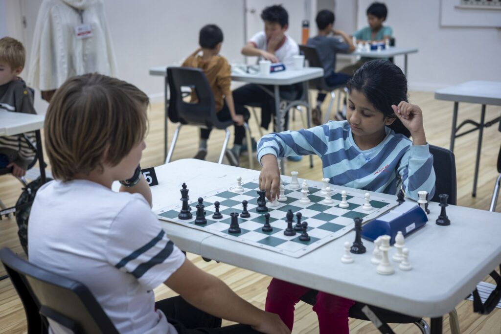 Girl and boy play chess together